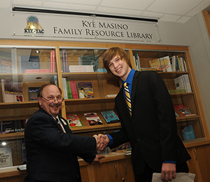 Brad Schaefer, M.D., chief of the UAMS Division of Genetics, left, and Kye Masino shake hands after unveiling a sign designating the Kye Masino Family Resource Library.